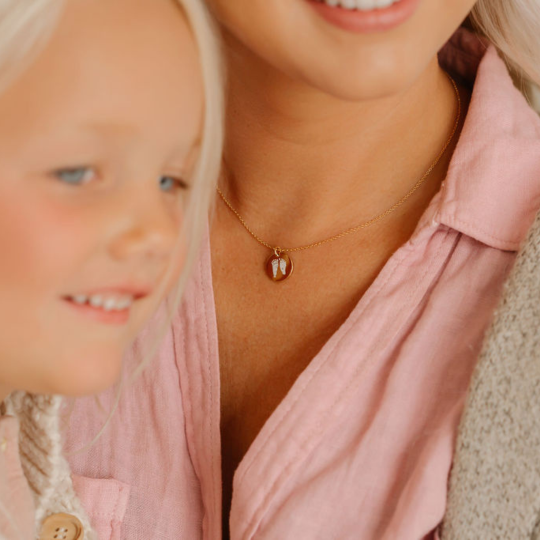 woman and daughter, woman is wearing a necklace with her daughters footprints