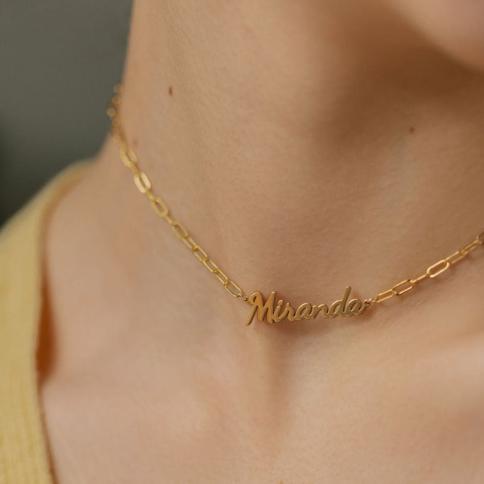 a lady is wearing name necklace with thick chains