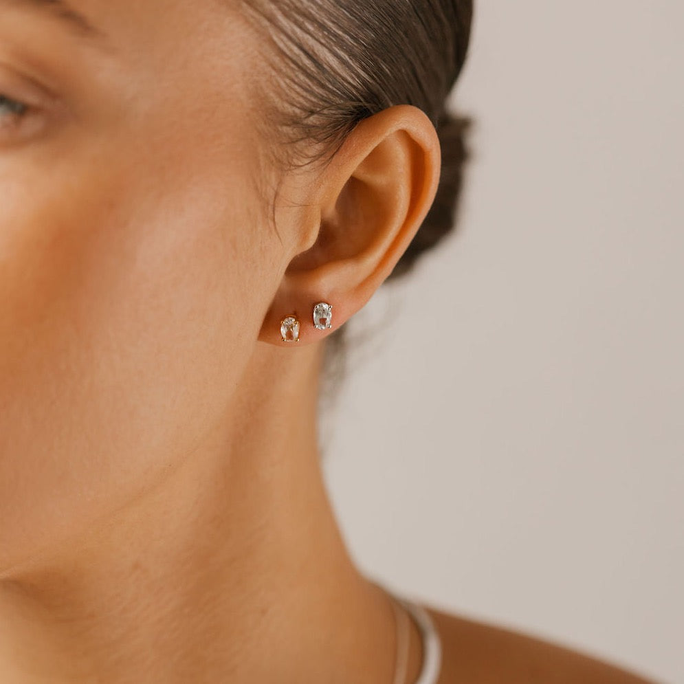 a woman is wearing natural white topaz stud earrings made in Canada