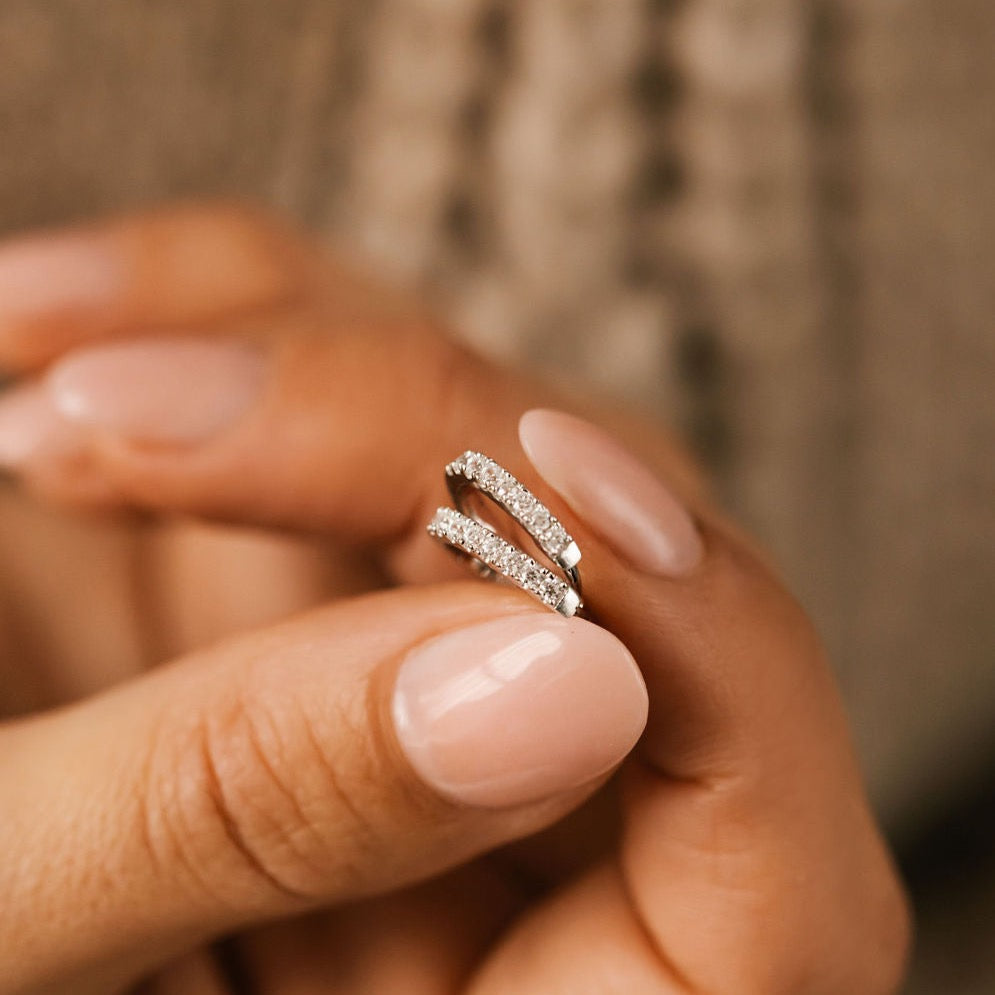 a woman is holding silver pave diamond hoops made in canada