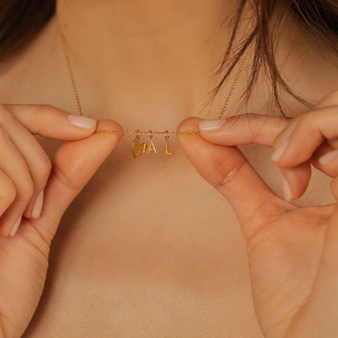 A woman is holding heart, A initial, L initial pendant necklace made in Edmonton