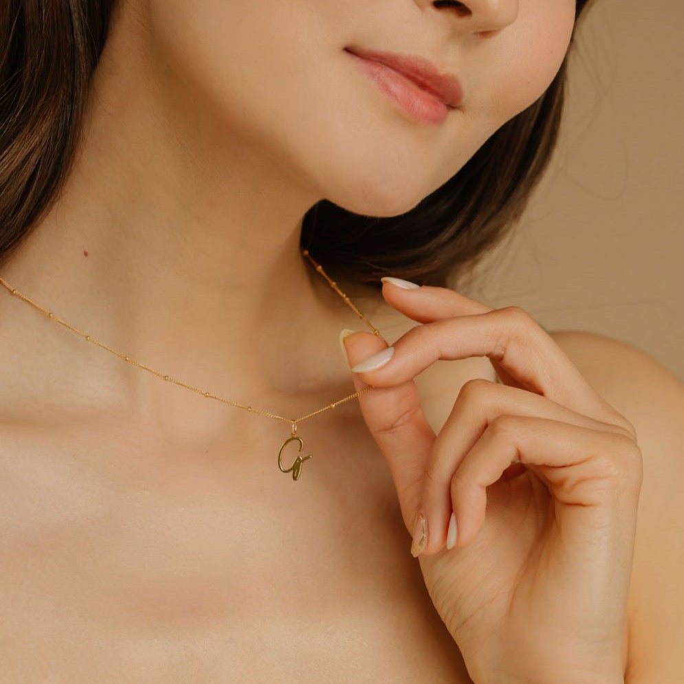 Model holding Initial Medium Charm Necklace