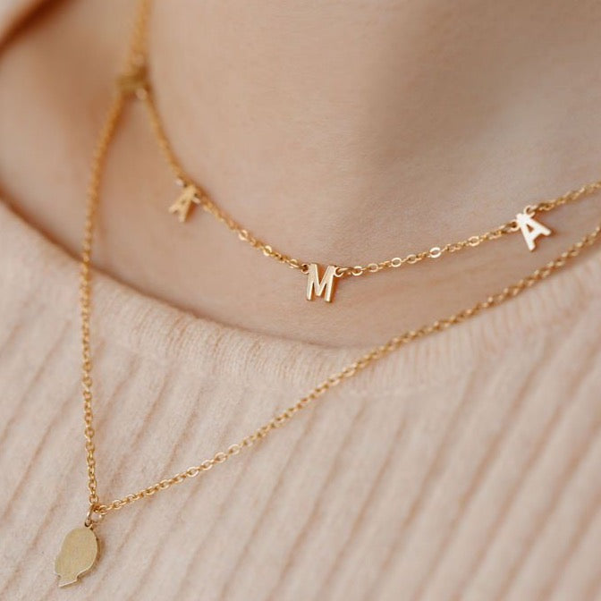 kids silhouette necklace layered with a MAMA letter necklace in solid gold