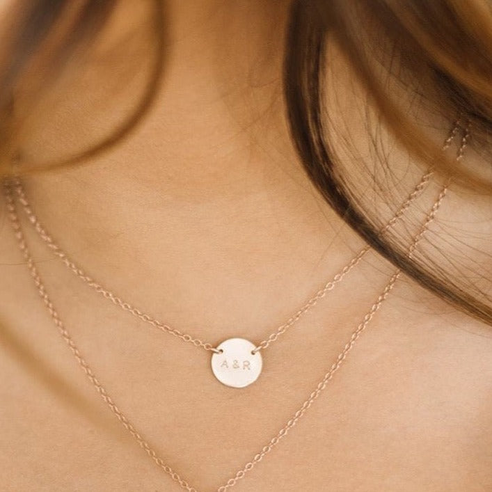 Woman wearing custom initial coin necklace and custom heart necklace